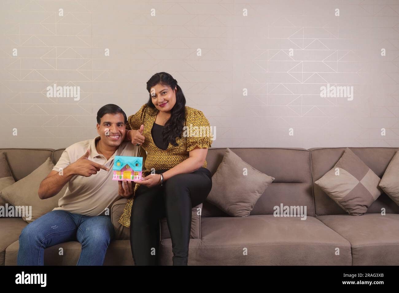 Felice coppia indiana seduta su un divano. La scelta di casa dei sogni diventa realtà. investimento nell'acquisto di una casa Foto Stock