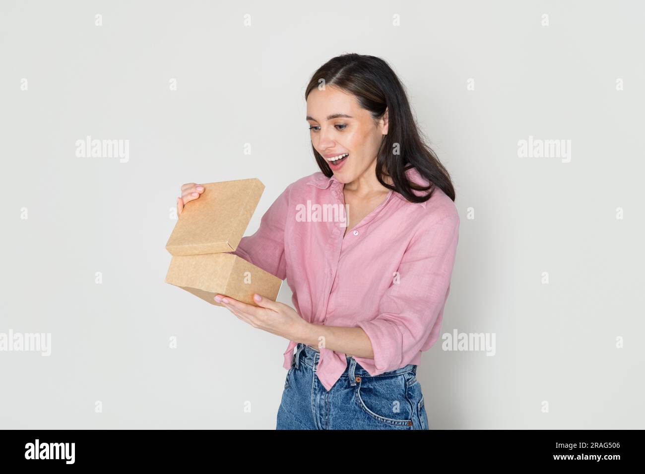 Un'emotiva e bella donna millenaria che apre una scatola di cartone Foto Stock