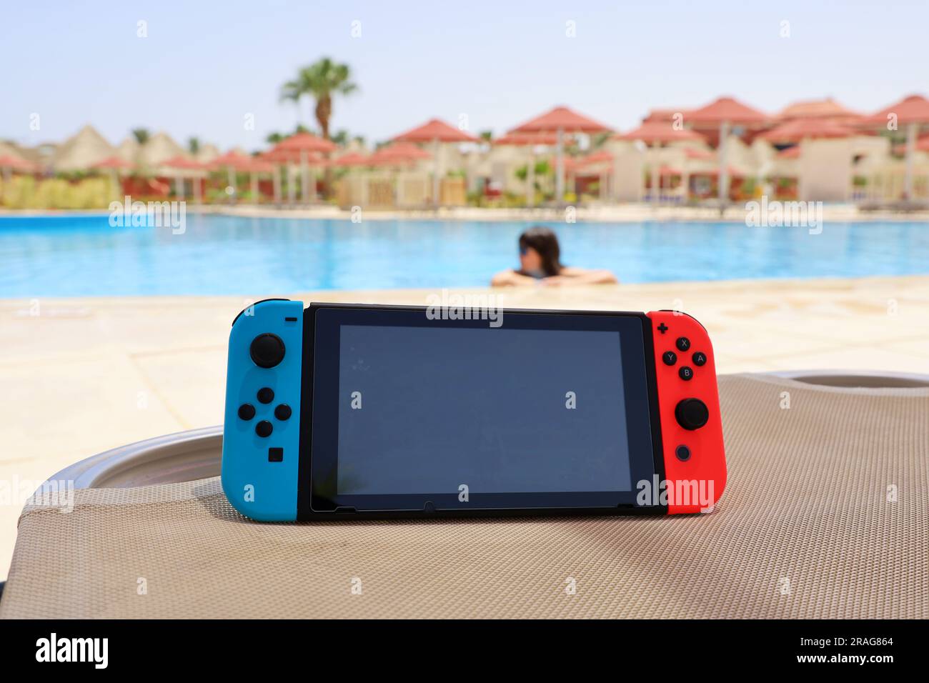 Console Nintendo Switch in modalità portatile su piscina e sfondo femminile Foto Stock