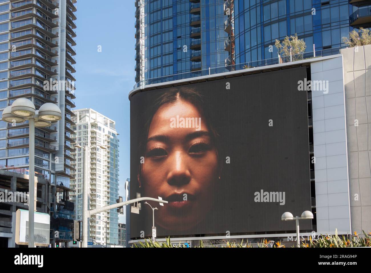 Il volto di una donna su un cartellone digitale che cambia di fronte al circa LA Apartments nel quartiere South Park di Downtown Los Angeles, CALIFORNIA, USA Foto Stock