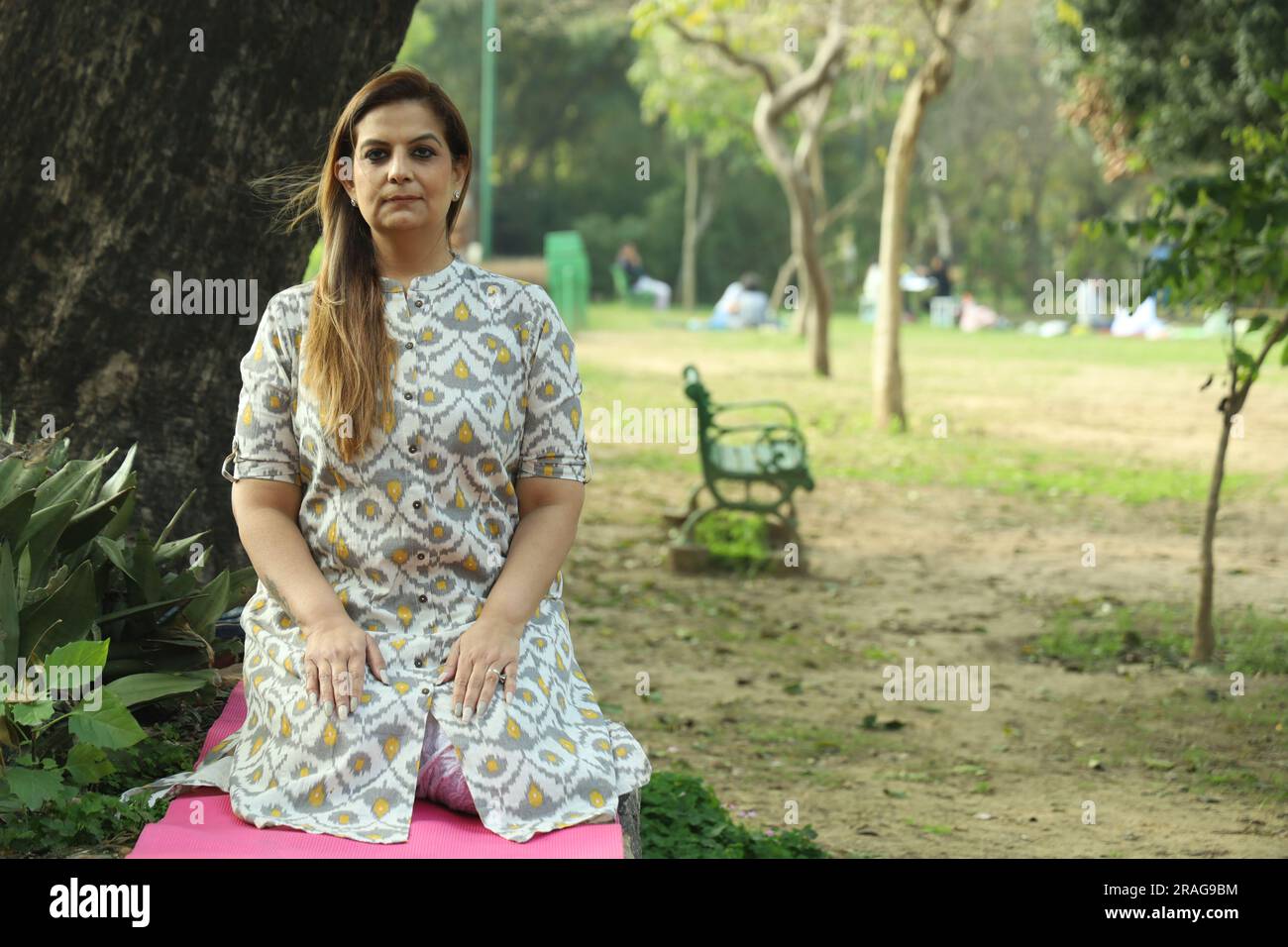 Bella donna indiana che fa yoga nel parco di giorno. Donna di mezza età che pratica yoga mattutino. Foto Stock