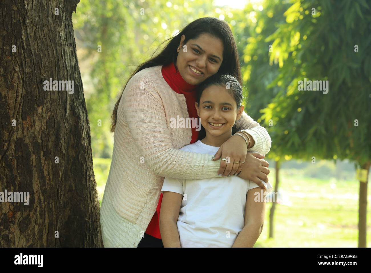 Madre e figlia indiane che si divertono insieme nel parco di giorno. La figlia è amata e si sente al sicuro con sua madre. Foto Stock