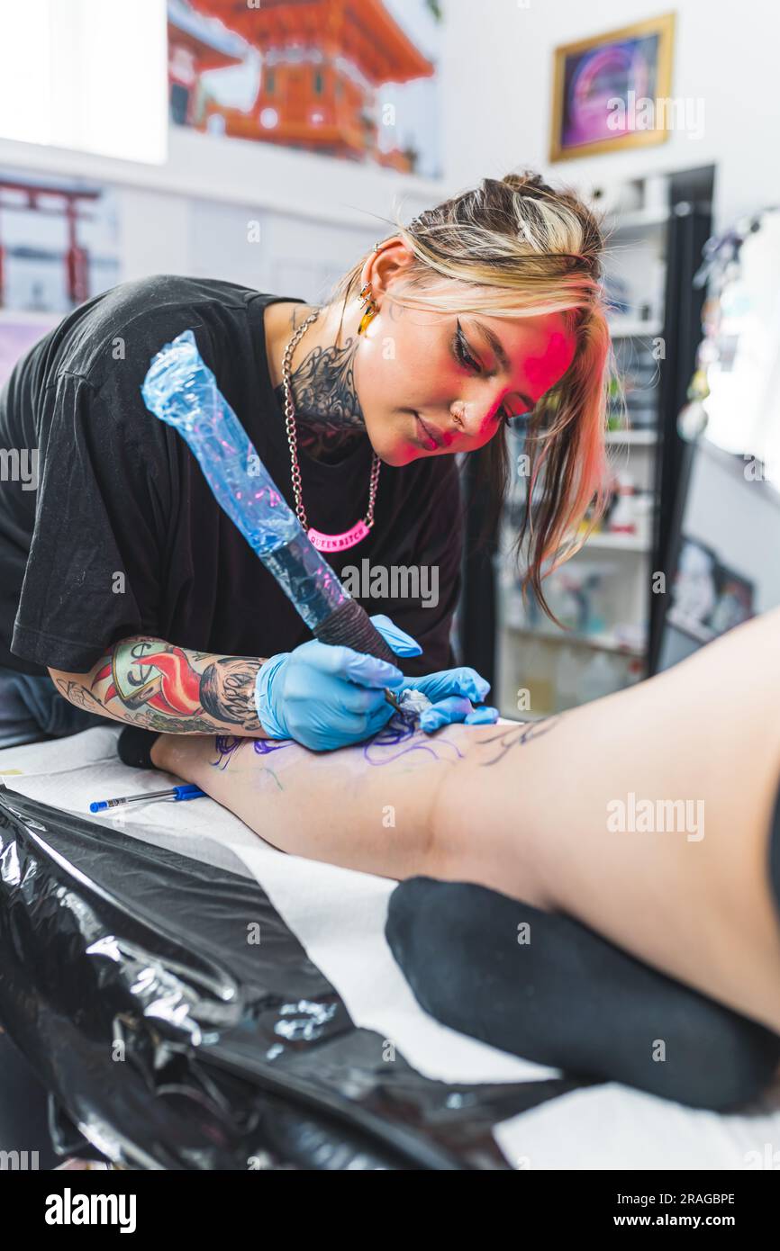 Ragazza maestra di tatuaggi caucasica che lavora con una macchina per  tatuaggio in studio, ripresa verticale media. Foto di alta qualità Foto  stock - Alamy