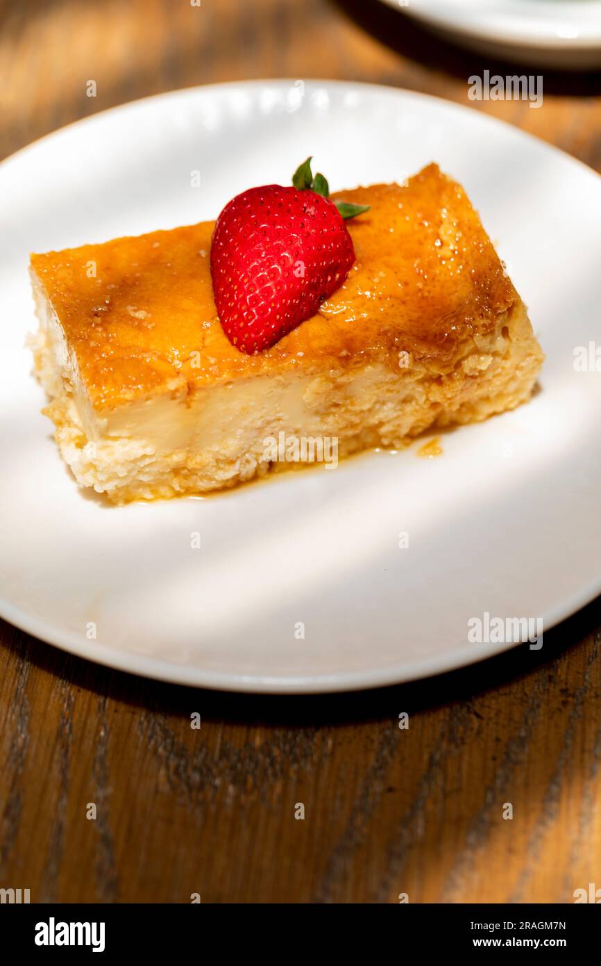 flan al caramello cotto in casa, con una fragola sulla parte superiore e caffè sul retro Foto Stock