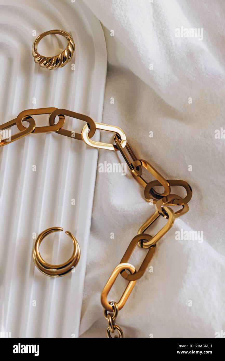 Collana con catena dorata e anello su vassoio geometrico, gioielleria minimalista Foto Stock