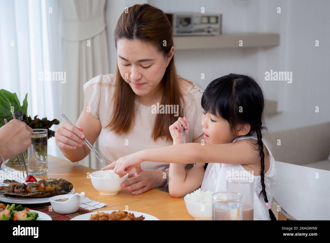 Felicità famiglia asiatica madre e padre e figlia mangiare cibo in cucina insieme a casa, genitori e bambini seduti a pranzo in soggiorno, legame un Foto Stock