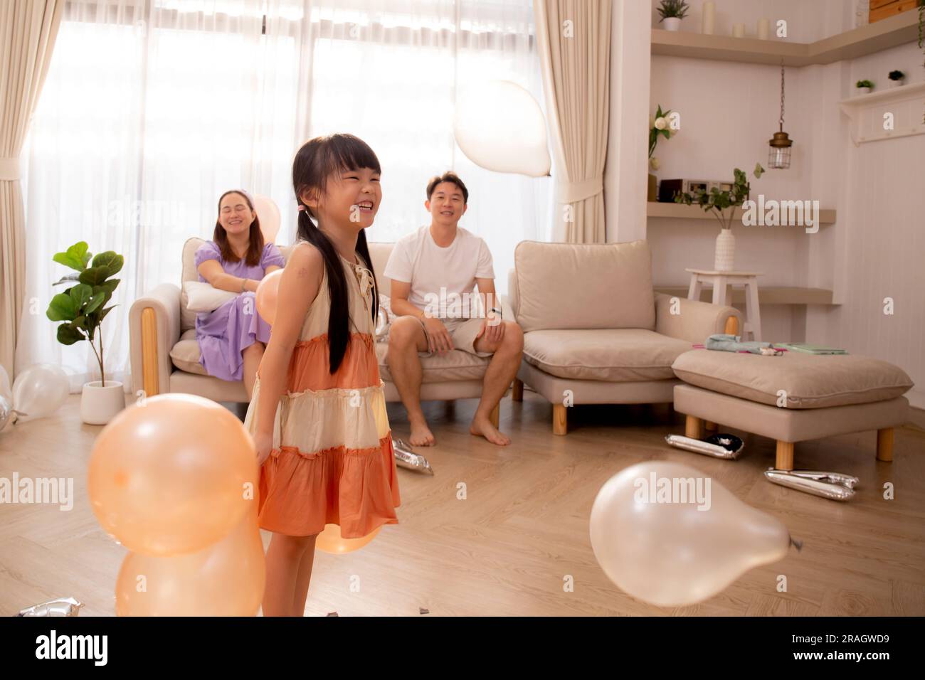 Felice famiglia asiatica padre e madre e figlia giocare mongolfiera con divertimento e la celebrazione nel soggiorno a casa, papà e mamma e bambino rilassarsi Foto Stock