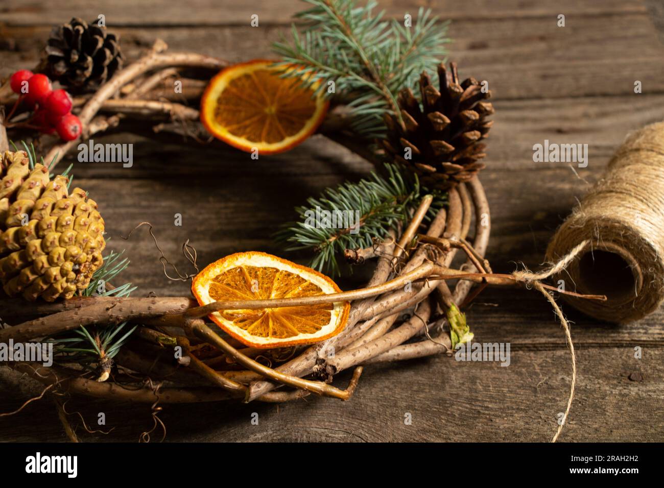 corona di viti natalizie e una palla di filo su un tavolo di legno, preparazione natalizia Foto Stock