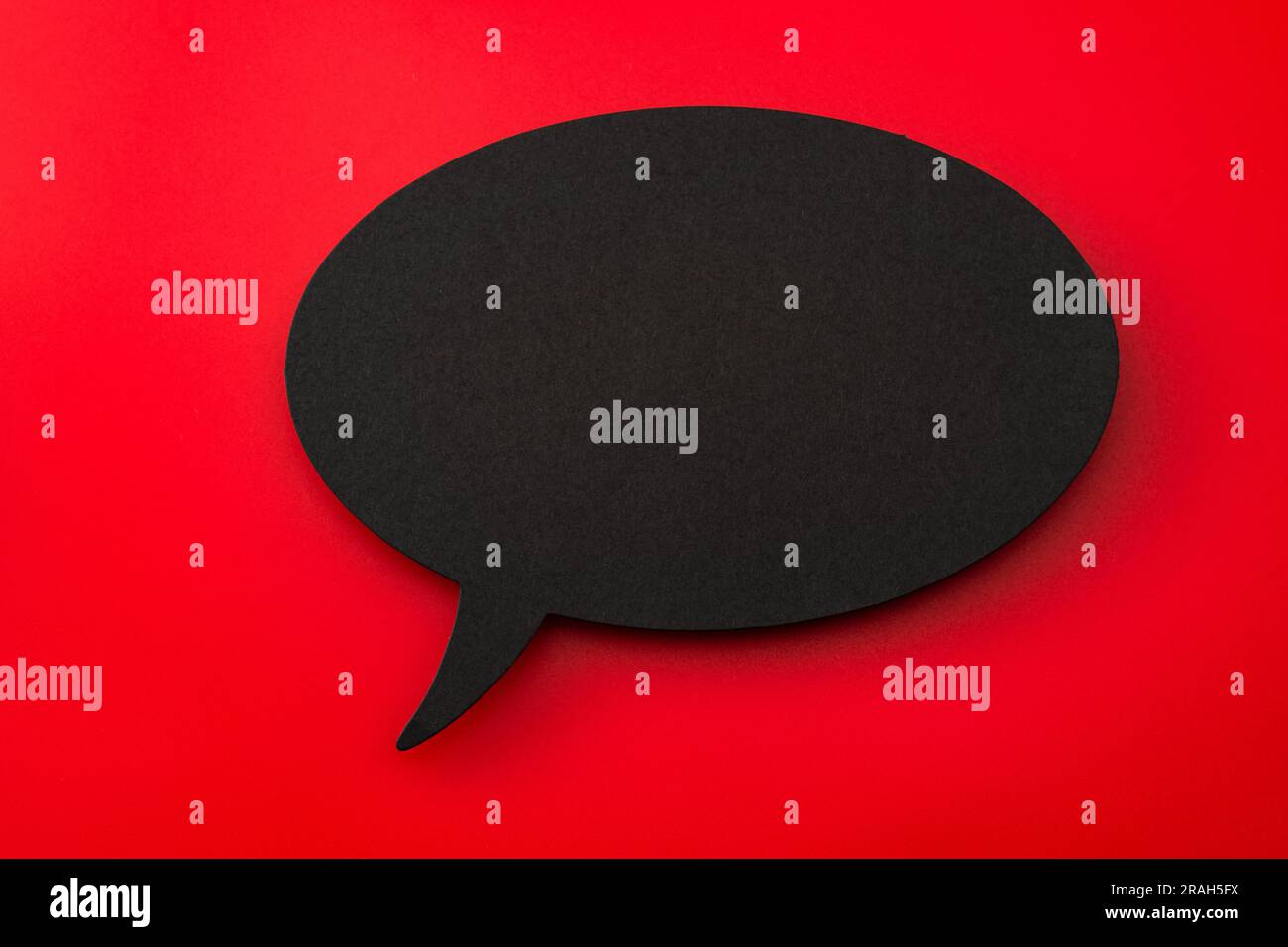 Ritaglio in cartone nero di bolla vocale vuota su sfondo rosso con spazio di copia: Concetto per elementi di progettazione di dialogo, espressione del simbolo di comunicazione Foto Stock