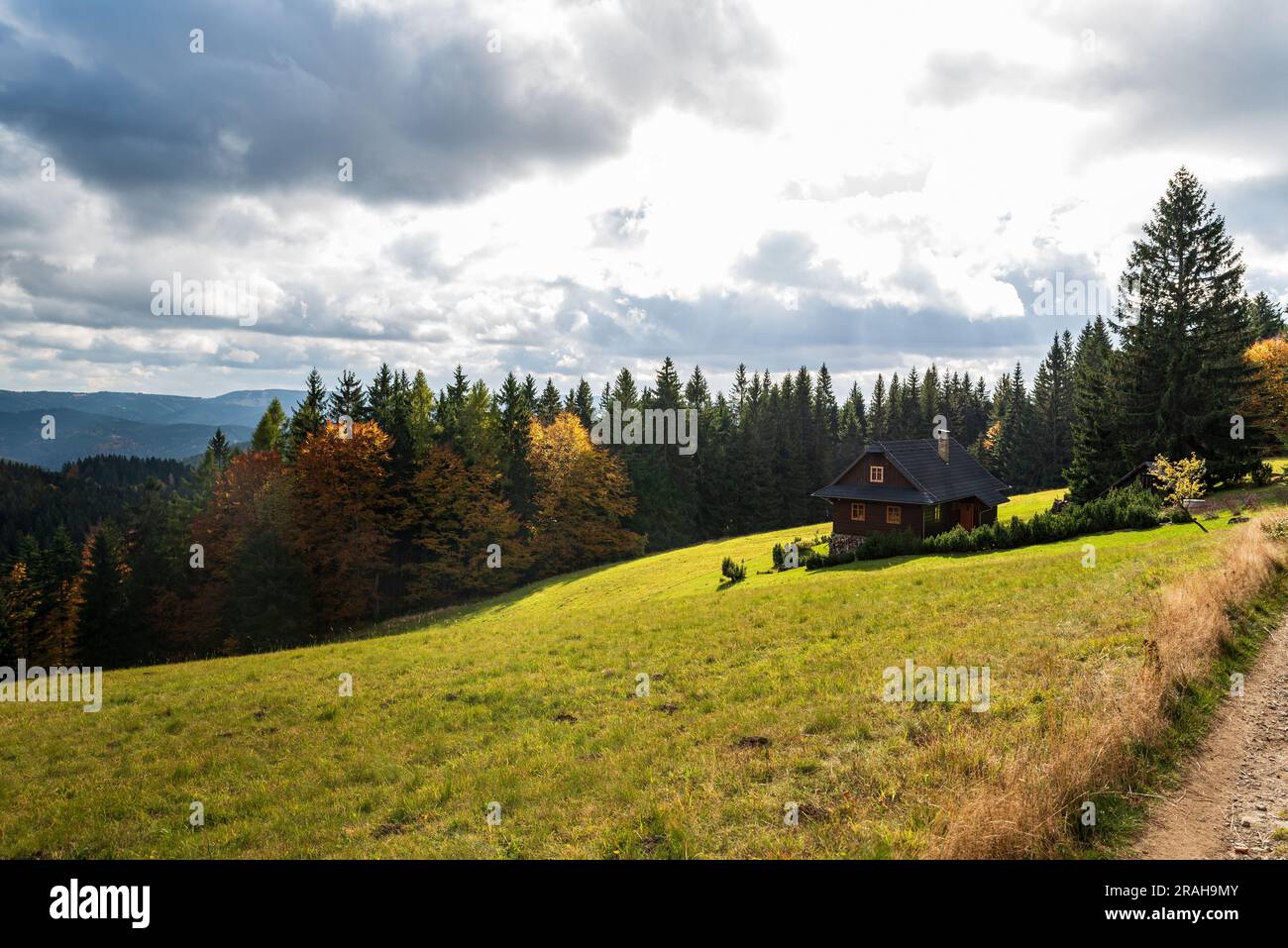 Chalet isolato su prato con colorata foresta autunnale intorno con colline sullo sfondo - Vsetinske vrchy Mountains sopra il villaggio Velke Karlovice in Foto Stock