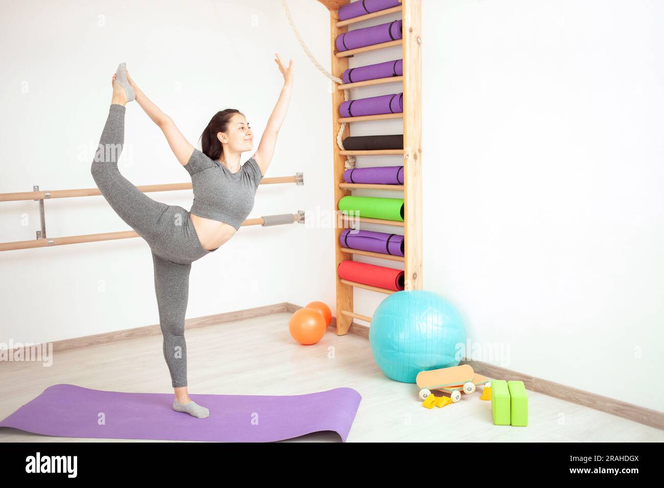 la giovane donna fa ginnastica in palestra. Stile di vita sano. tappetino viola bella posa. Foto Stock