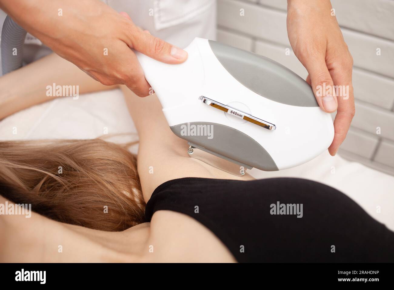 Il cosmetologo rimuove i capelli sulle ascelle della donna utilizzando il laser. Epilazione in salone, procedura cosmetica, concetto di pelle morbida e liscia. laser a diodi. Foto Stock