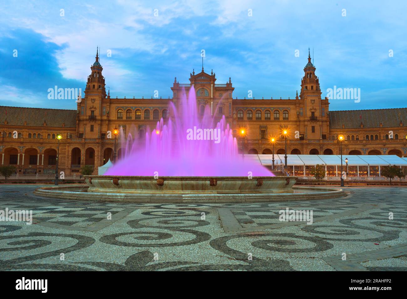 Di notte, Plaza de Espana a Siviglia abbaglia con una fontana illuminata, dove le acque viola creano una scena affascinante, creando un'accattivante Foto Stock