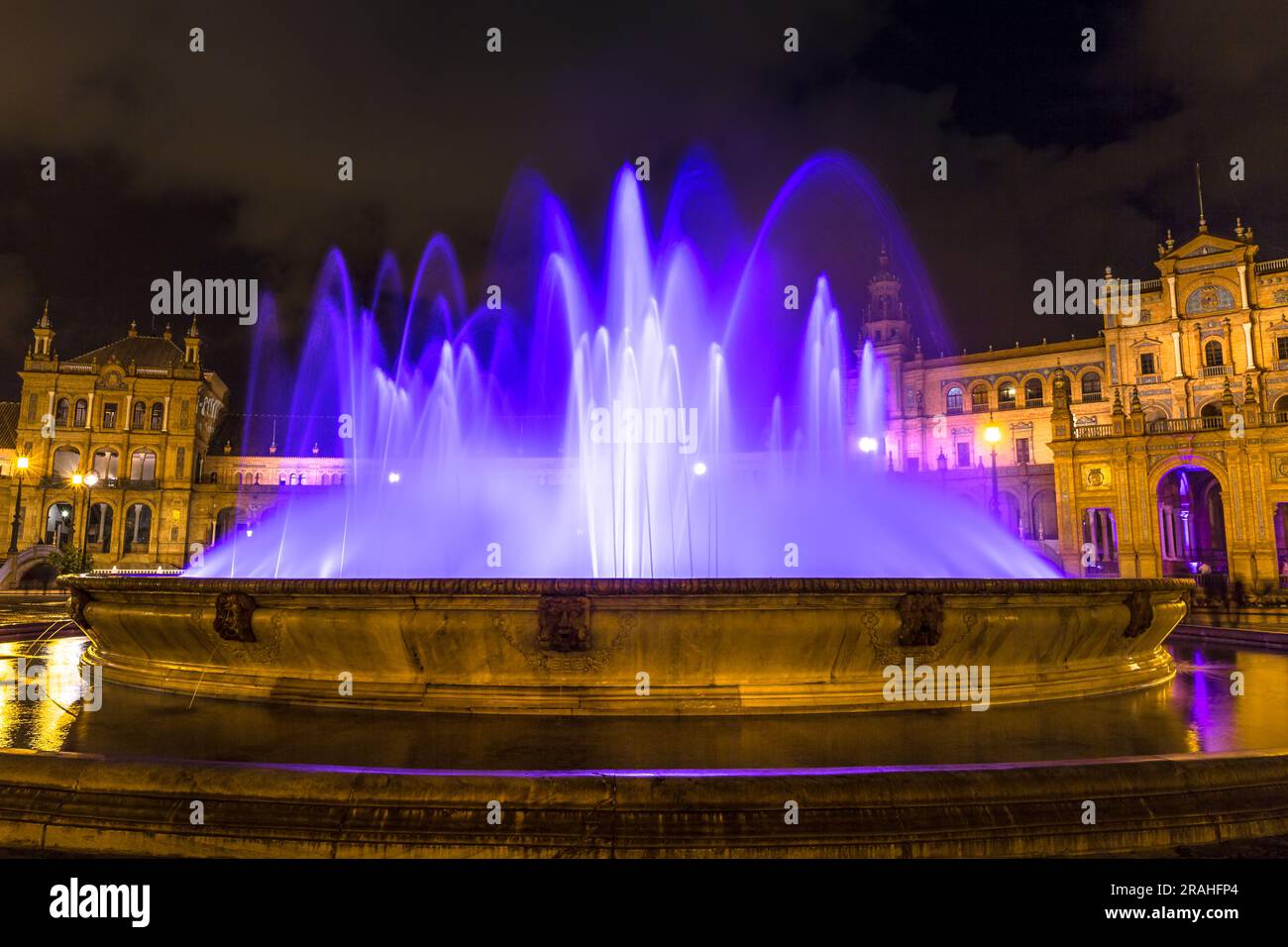 Mentre l'oscurità scende su Plaza de Espana di Siviglia, la fontana assume una trasformazione magica, crogiolandosi nel delicato bagliore di illuminazione di Foto Stock