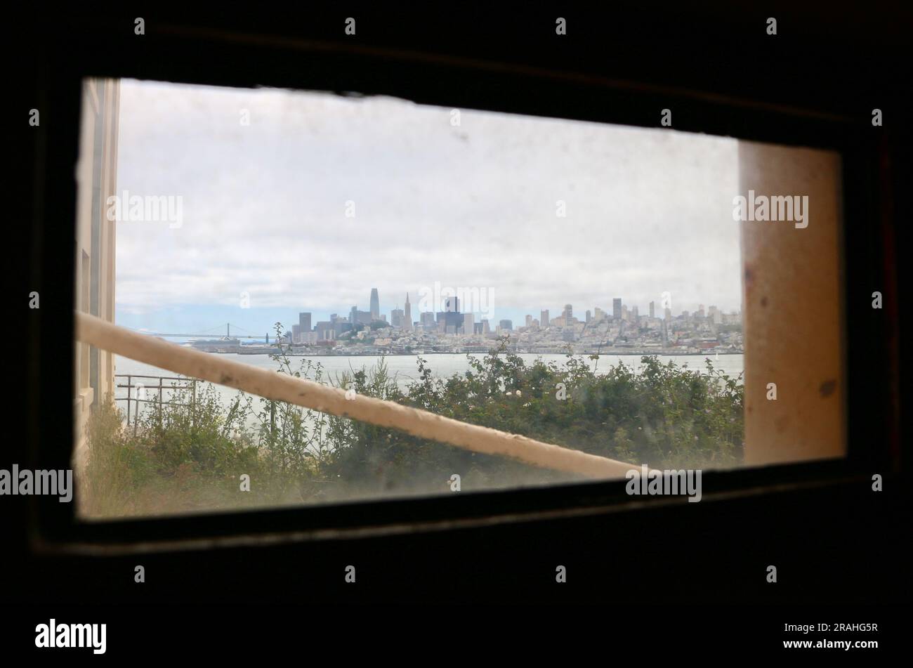 Guardando attraverso una finestra con vista della baia e dello skyline di San Francisco dal penitenziario federale di Alcatraz San Francisco California USA Foto Stock