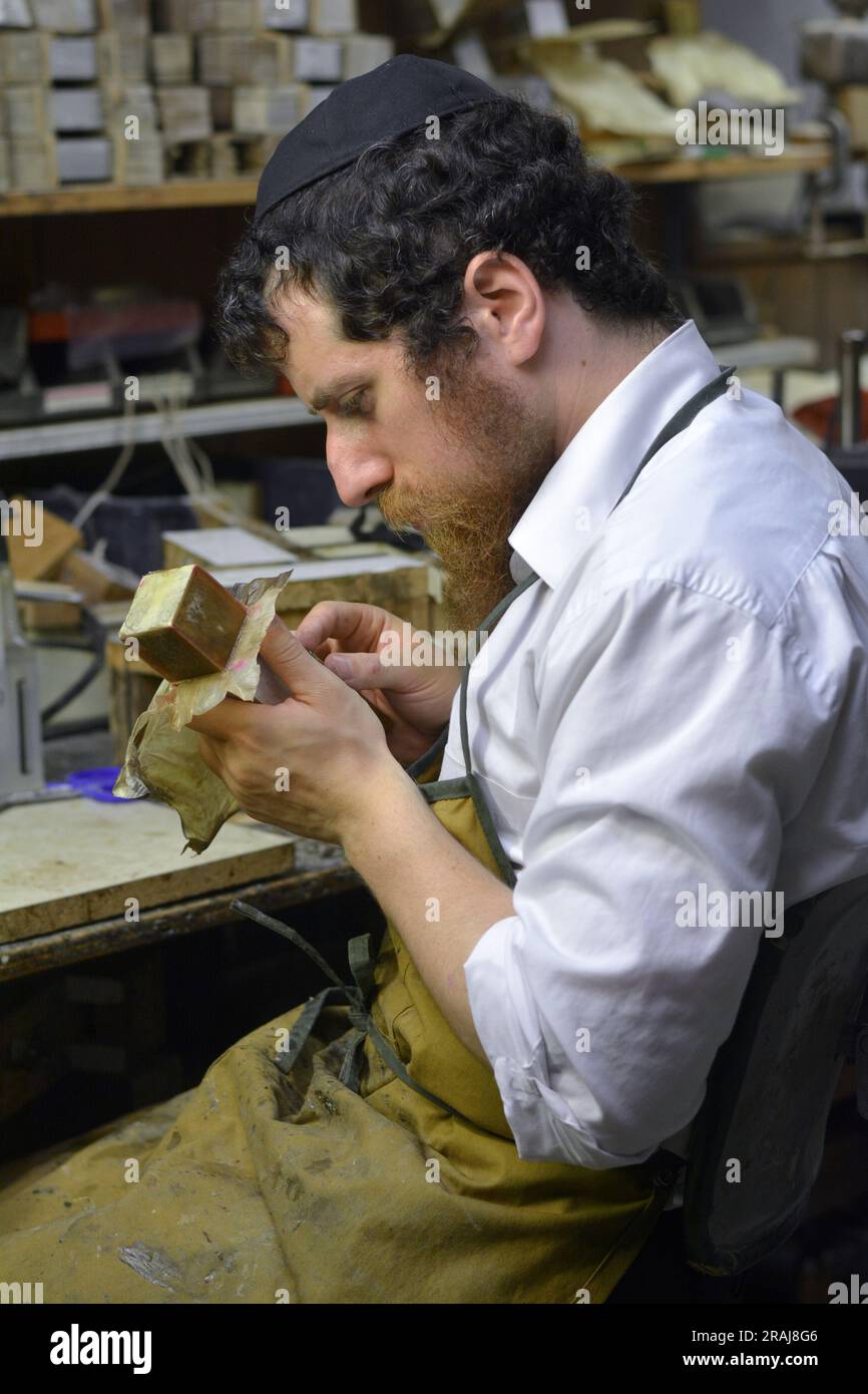 Un mastro artigiano chassidico crea cuoio mentre produce tefillin nel suo laboratorio seminterrato a Brooklyn, New York Foto Stock