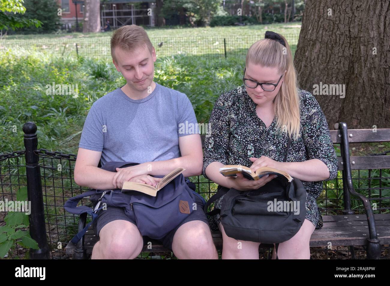 LETTURA. Una coppia di turisti si rilassa nel parco di Washington Square, ognuno leggendo da un libro. A Manhattan, New York. Foto Stock