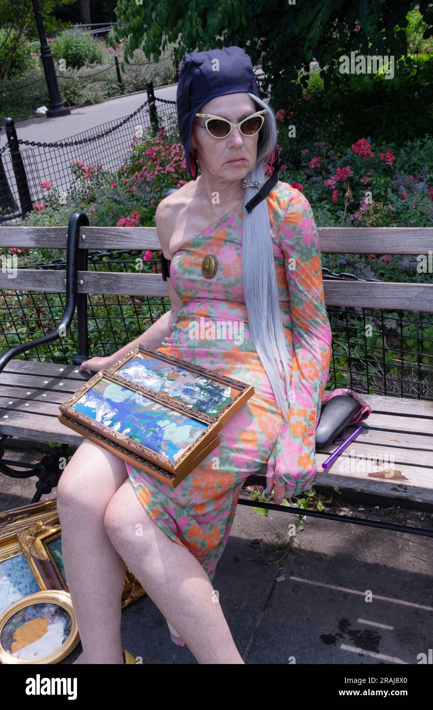Un'artista donna anziana con uno stile personale distinto, vende piccoli pezzi d'arte originali seduti su una panchina nel Washington Square Park a Manhattan. Foto Stock