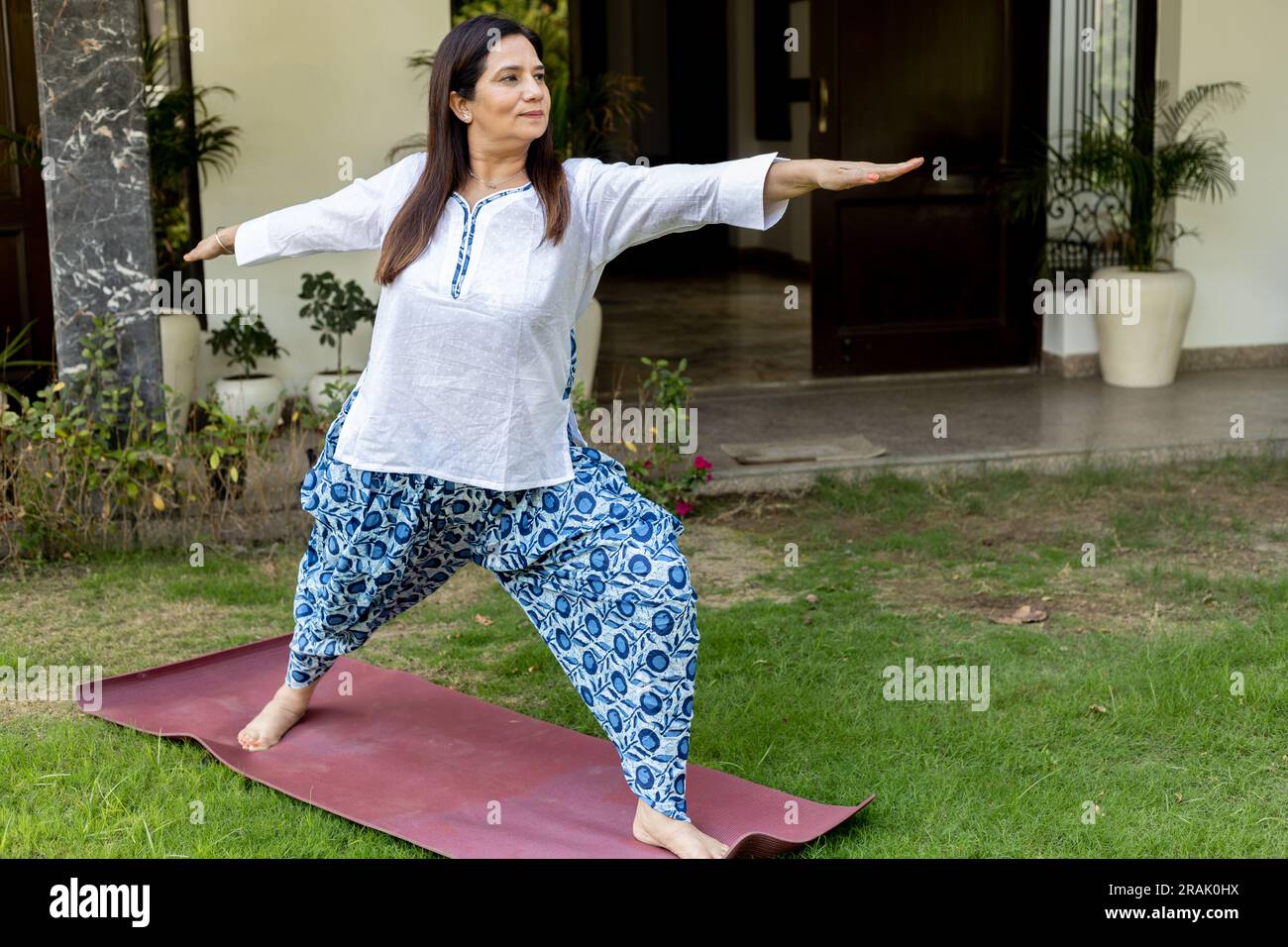 Donna matura indiana che fa yoga a casa giardino Foto Stock