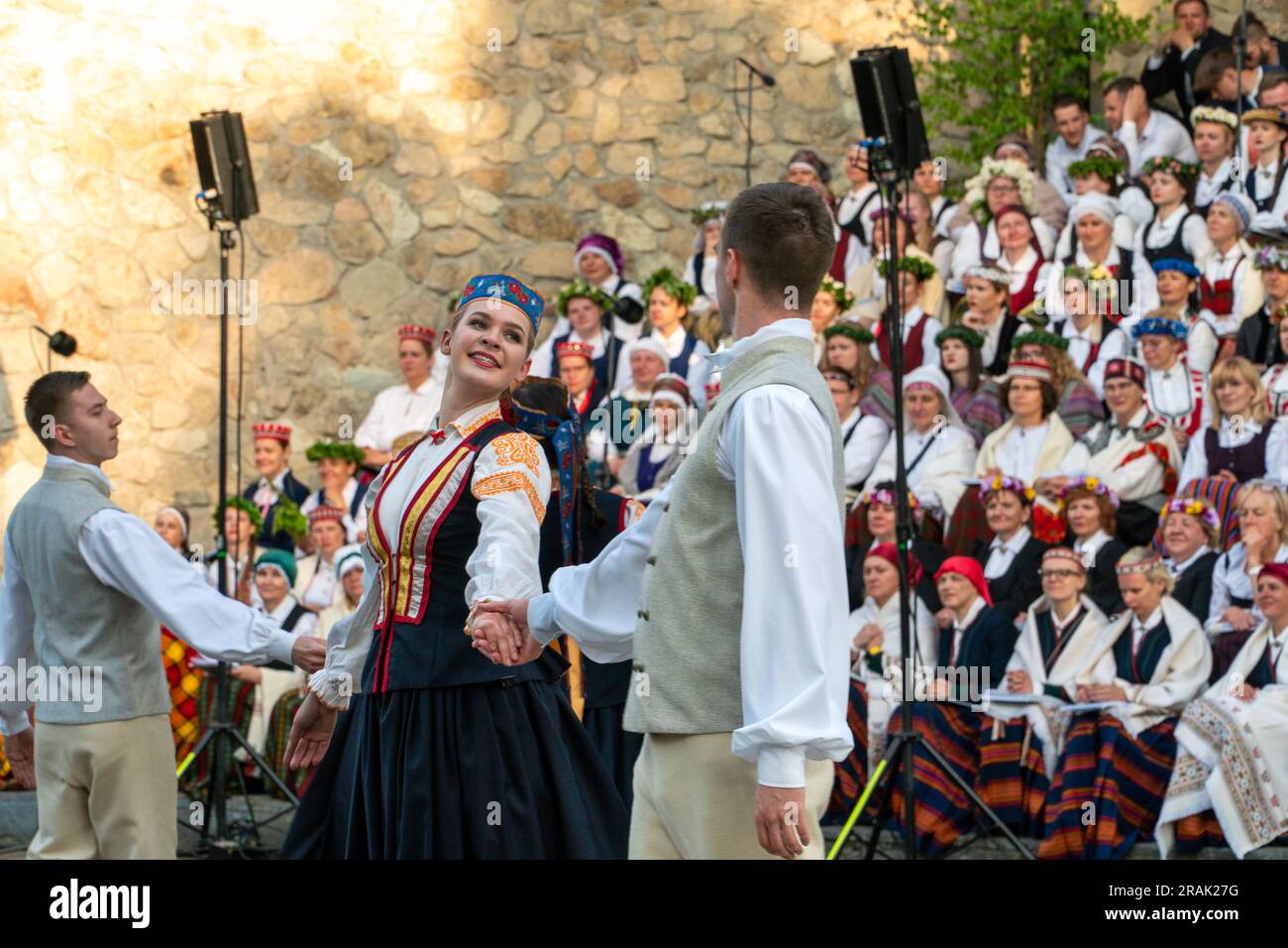 Dobele, Lettonia - 27 maggio 2023. Un paio di giovani ballerini popolari in primo piano davanti ai cantanti corali popolari durante la XXVII Nationwide Lettone Song An Foto Stock