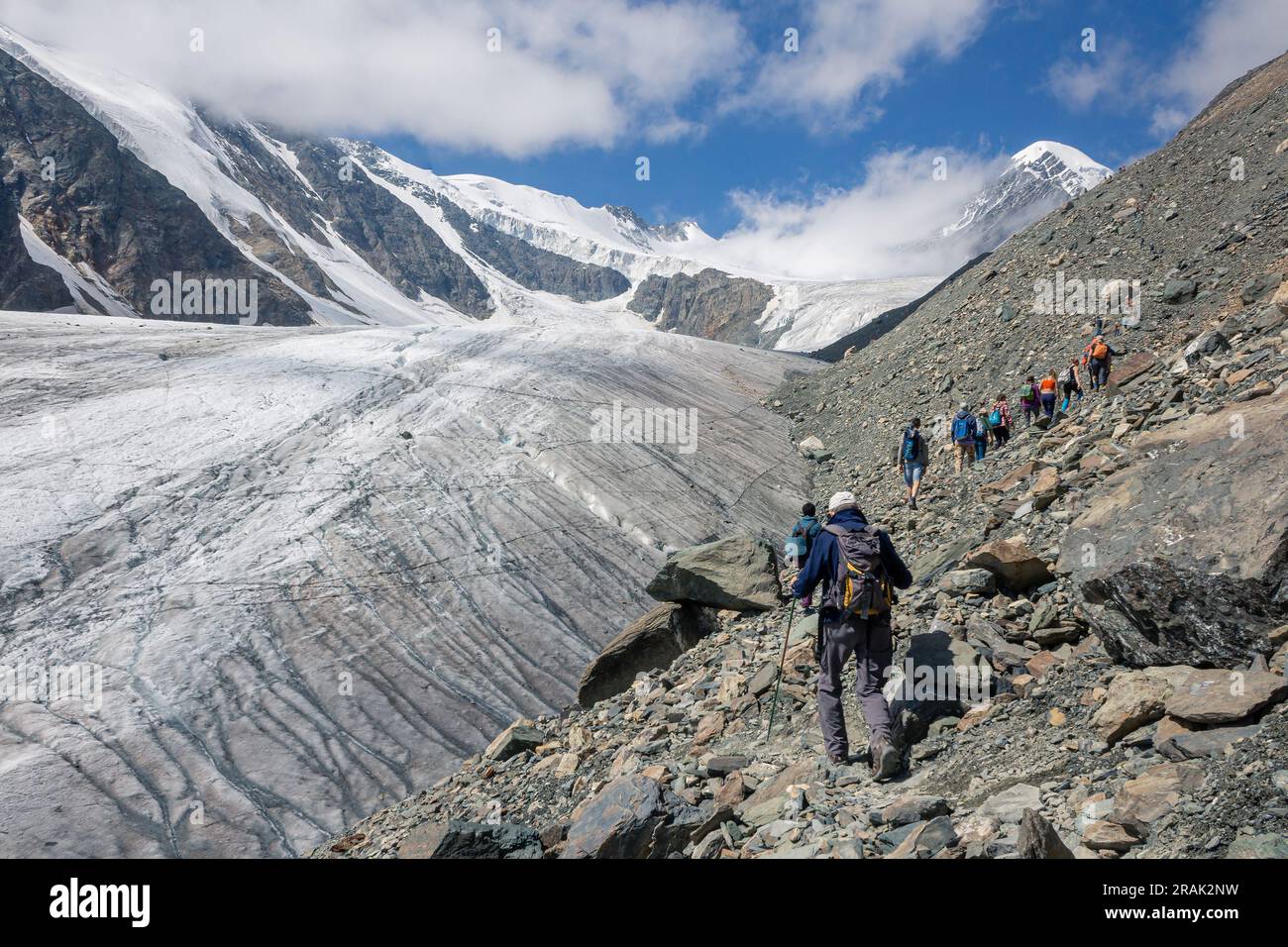 Un gruppo di turisti sale lungo un ghiacciaio nelle montagne dell'Altai. Aktru al giorno d'estate. Foto Stock