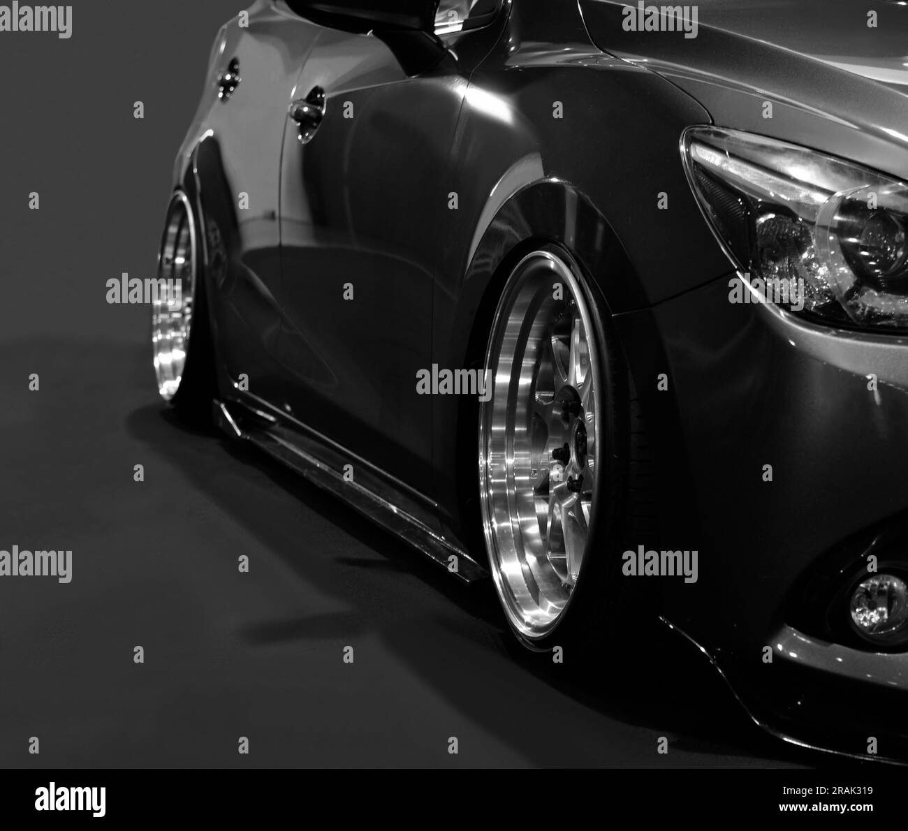 Fari anteriori di auto nera modificata su sfondo nero Foto Stock