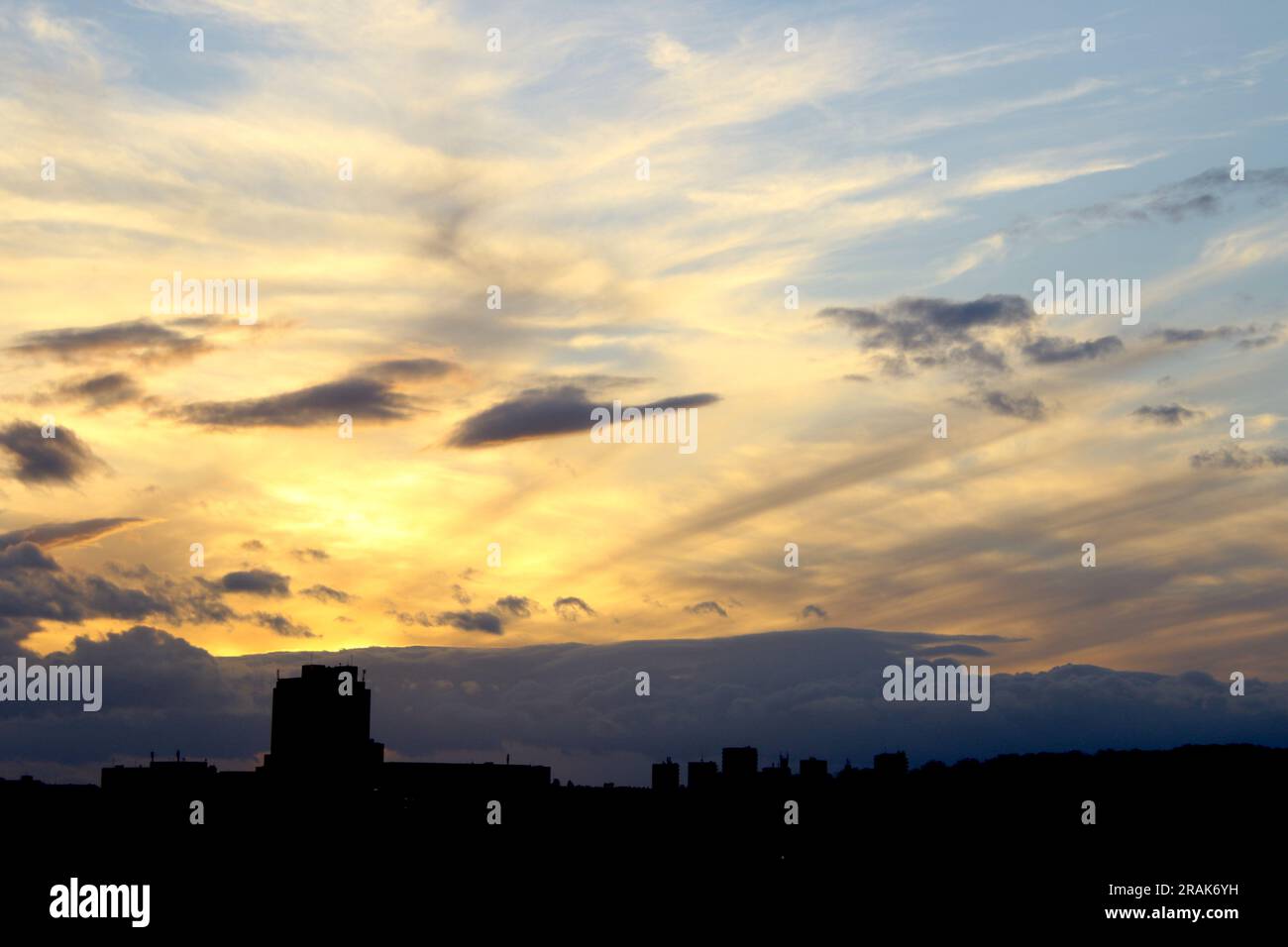 Un mix di formazioni nuvolose e colori brillanti di un tramonto serale di dicembre in città Foto Stock