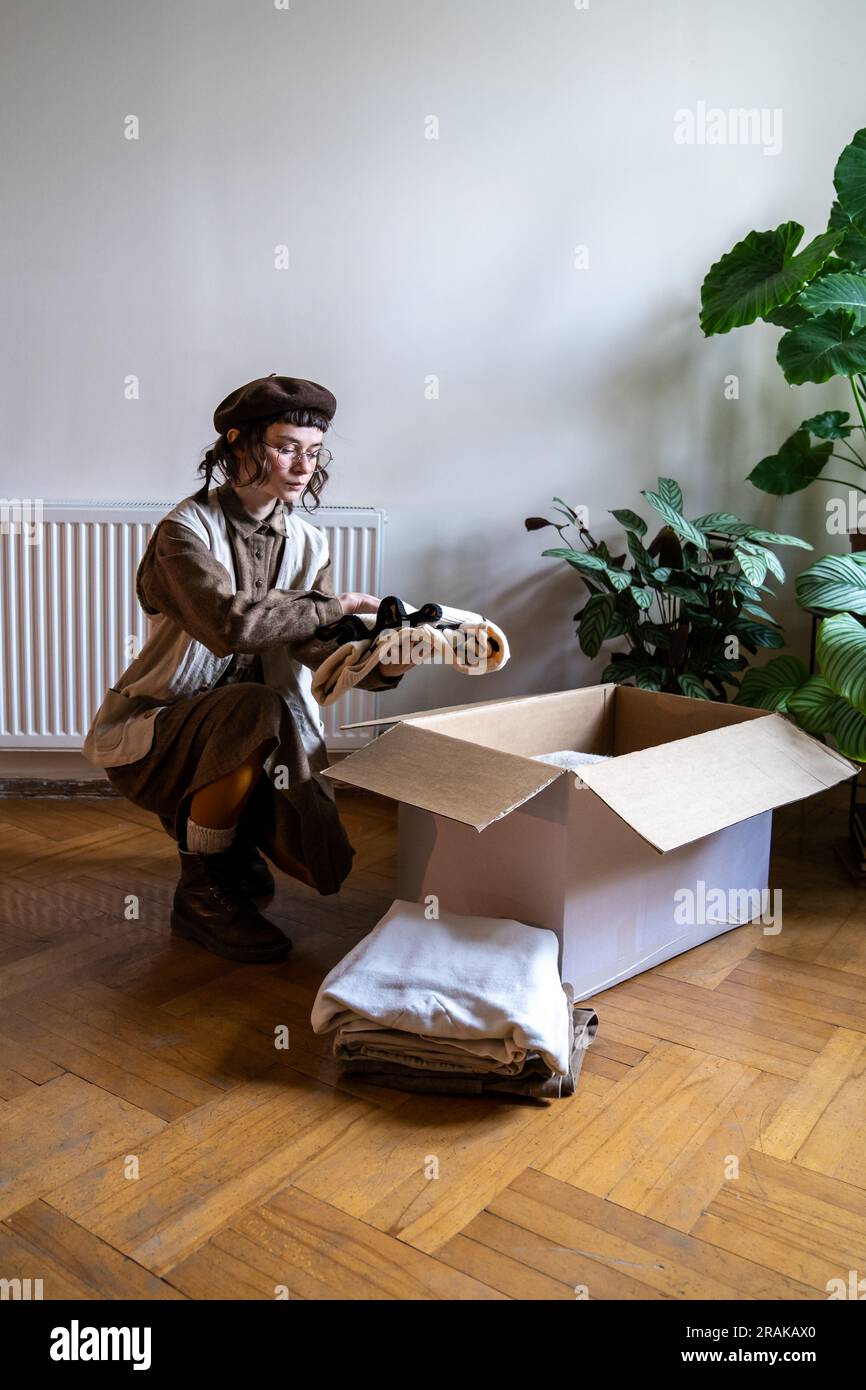 Girl eco-attivista confeziona oggetti da riciclare nella scatola. Consumo consapevole, vestirsi in modo da salvaguardare l'ambiente. Foto Stock