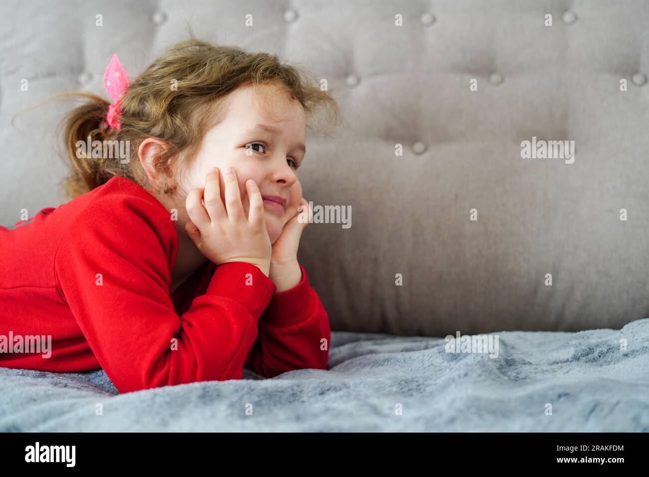 Simpatica bambina stesa sul letto a casa, felice infanzia Foto Stock