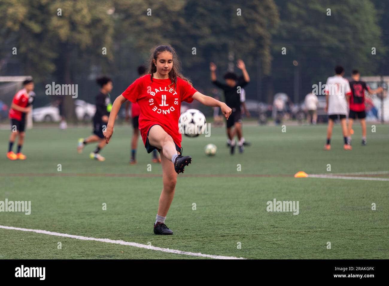 Una ragazza pratica le sue abilità calcistiche durante una serata su un campo comunitario del centro cittadino Foto Stock