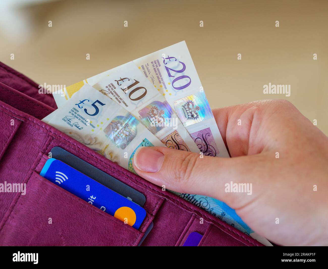 Primo piano della mano che prende banconote da libbra in contanti dal portafoglio Foto Stock