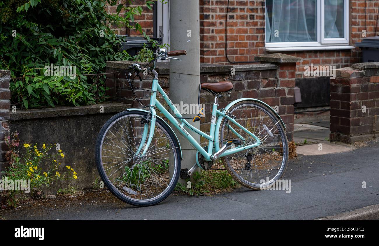 Una bicicletta incatenata e fissata saldamente a un lampione in una strada residenziale Foto Stock
