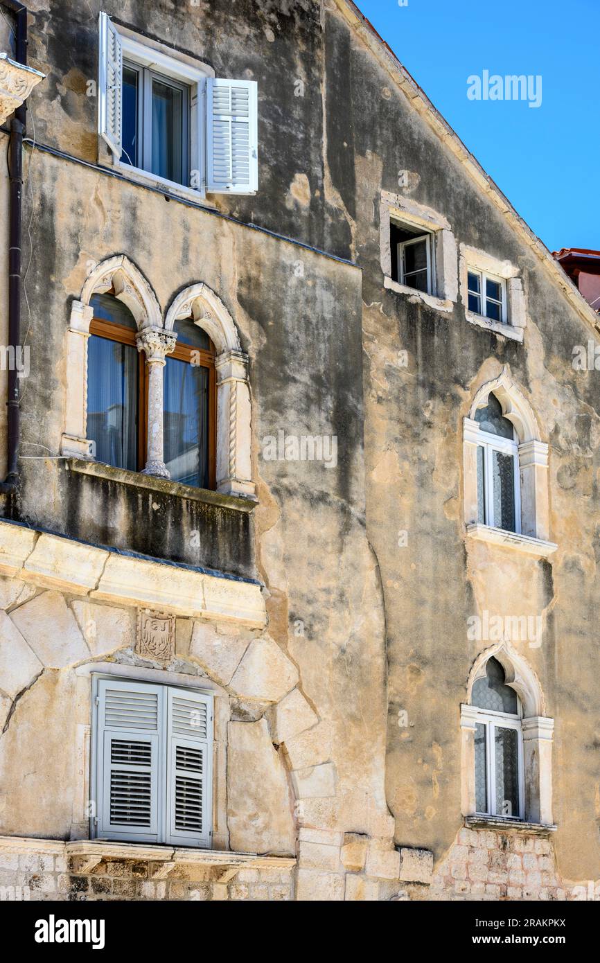 Facciata di un vecchio edificio con finestre decorative nella città vecchia medievale di Spalato all'interno delle mura del Palazzo di Diocleziano, Spalato, Dalmazia, Croazia. Foto Stock