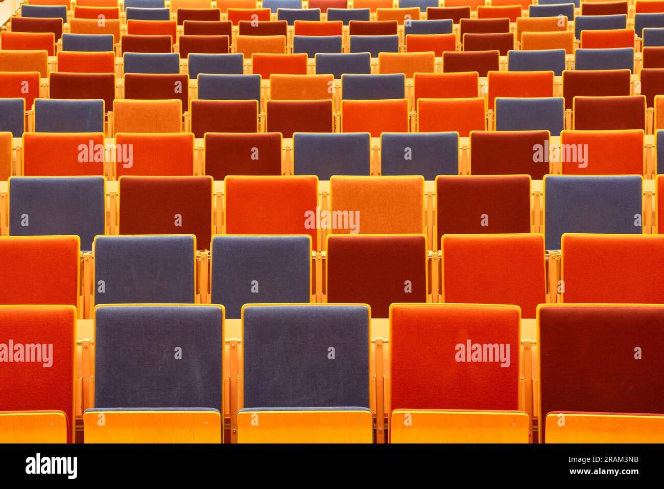 Sedie colorate in una sala conferenze di un'università. Prospettiva e colori in stile Wes Anderson. Foto Stock