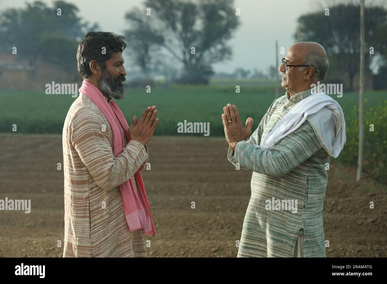 Splendida composizione di due agricoltori indiani in piedi nel campo con le mani piegate. Concetto agricolo che ritrae gli agricoltori al lavoro. Foto Stock