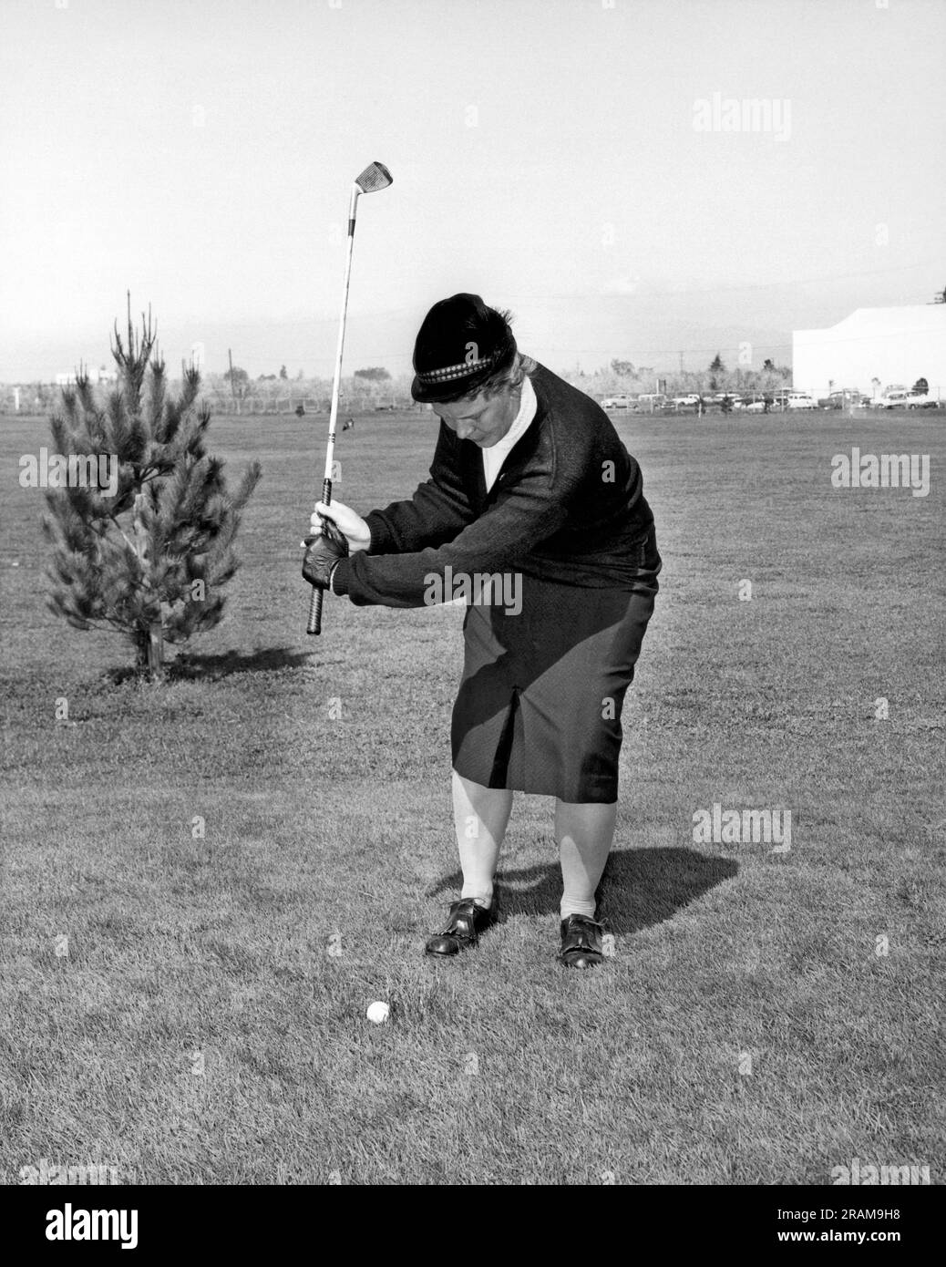 California: c. 1956. Una golfista si prepara a colpire la sua palla. Foto Stock