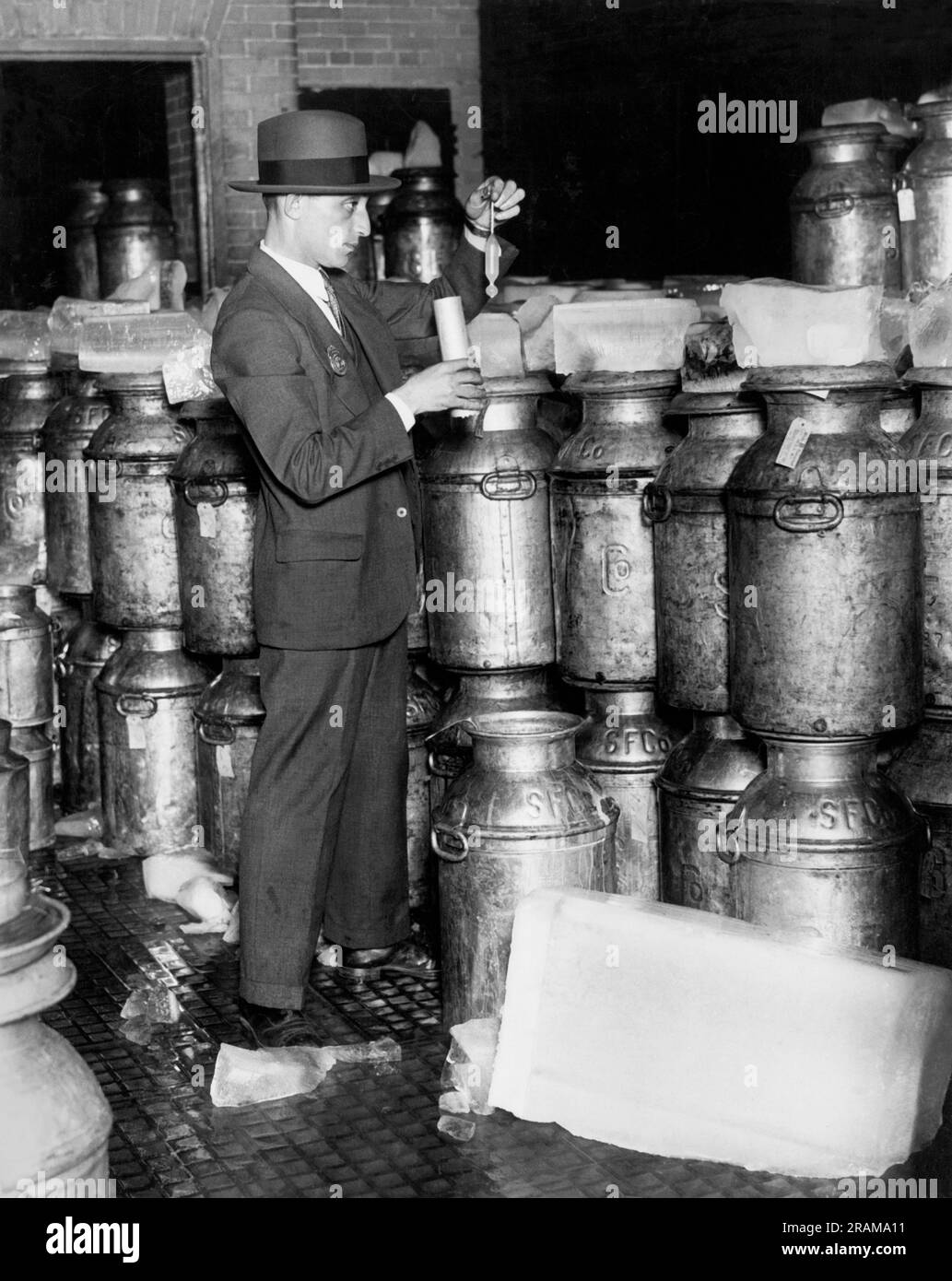 New York, New York: c. 1926 Un ispettore del Dipartimento della salute di New York prende una lettura del lattometro sulla piattaforma di distribuzione di un impianto di pastorizzazione. Misura il peso specifico e quindi la ricchezza del latte. Foto Stock