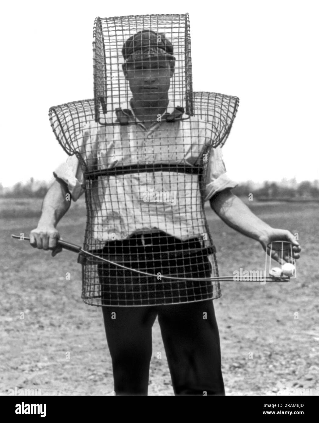 California: c. 1925. Caddy Mozart Johnson indossa il più recente dispositivo di sicurezza visto sui collegamenti della California. È stato progettato per proteggere caddie e palle da palline da golf selvagge e erranti. Foto Stock