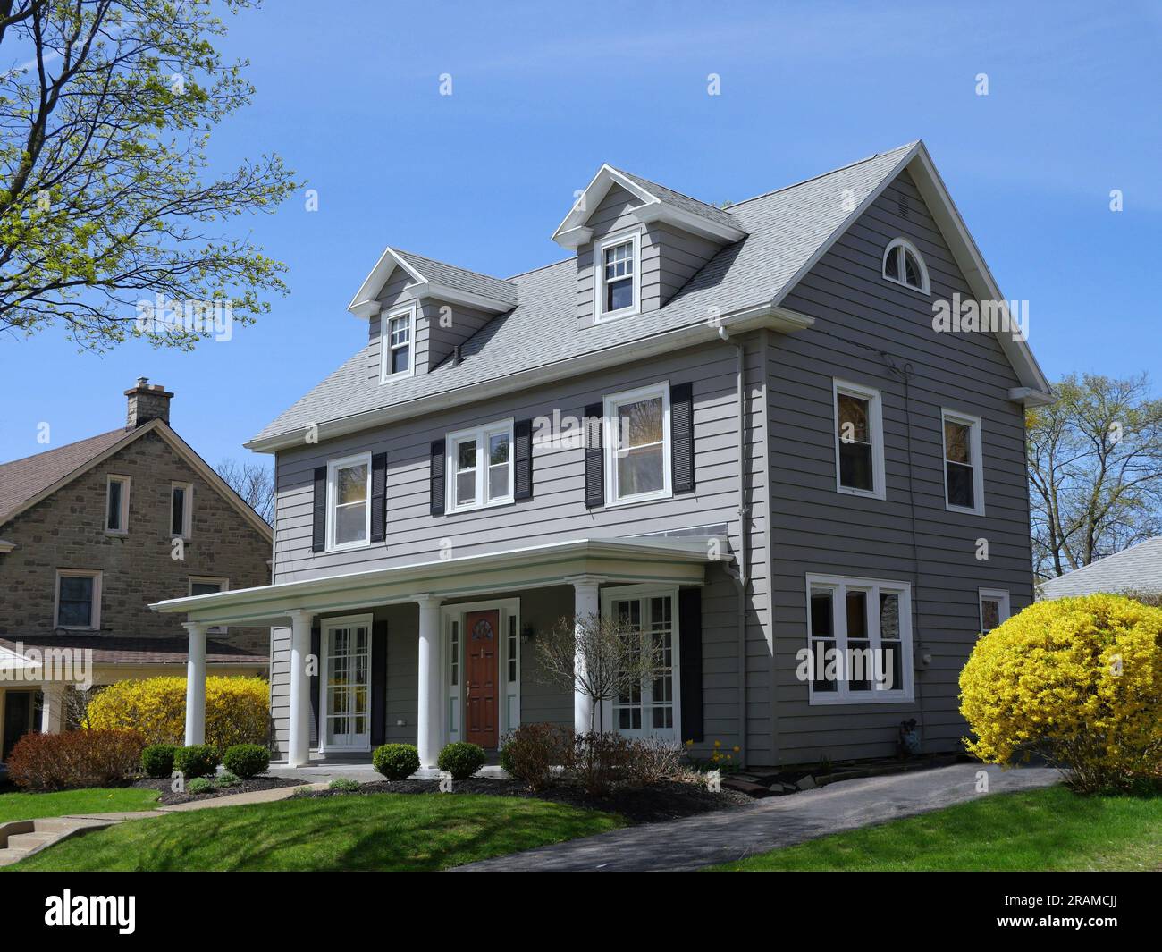 Casa a due piani con finestre dormitori e cespugli gialli di forsicia che fioriscono in primavera Foto Stock