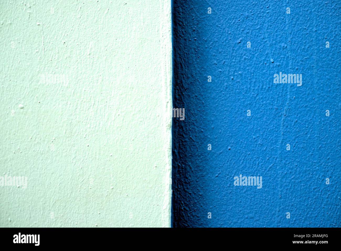 Due tonalità di bande di colore blu su una parete appena dipinta in luce dura, centrata con due parti uguali. Foto Stock