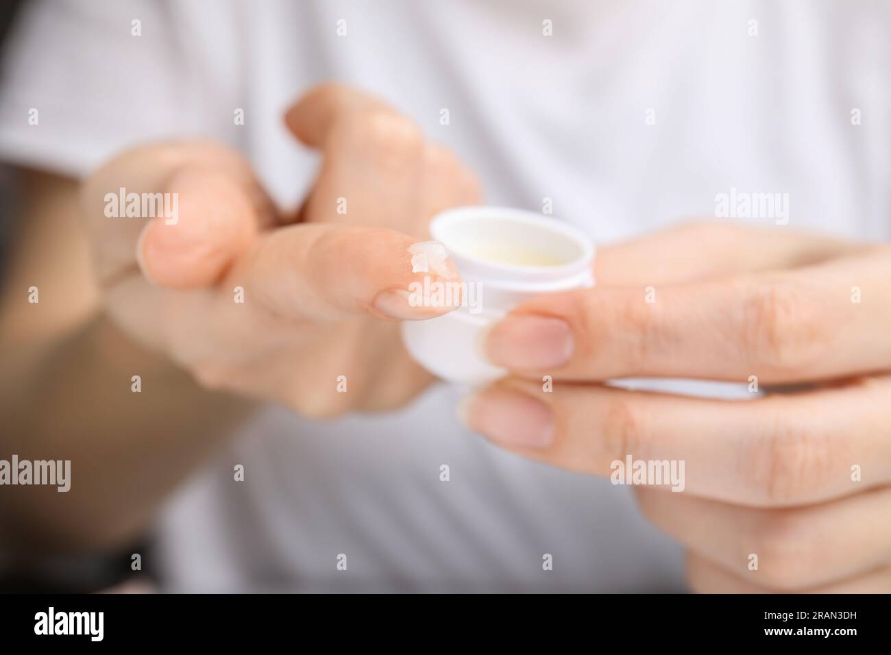 Donna che prende petrolatum cosmetico dal vaso, primo piano Foto Stock