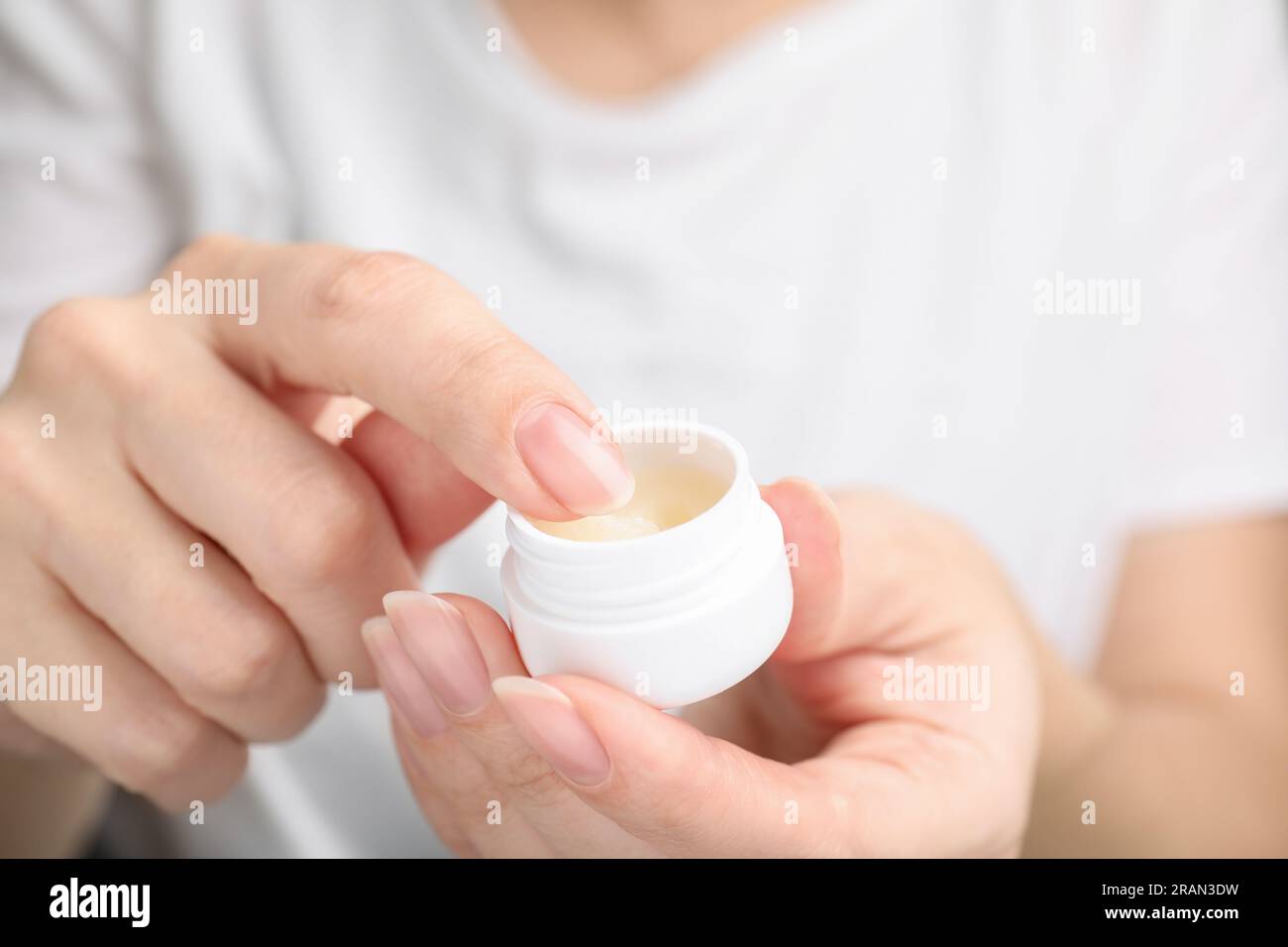 Donna che prende petrolatum cosmetico dal vaso, primo piano Foto Stock