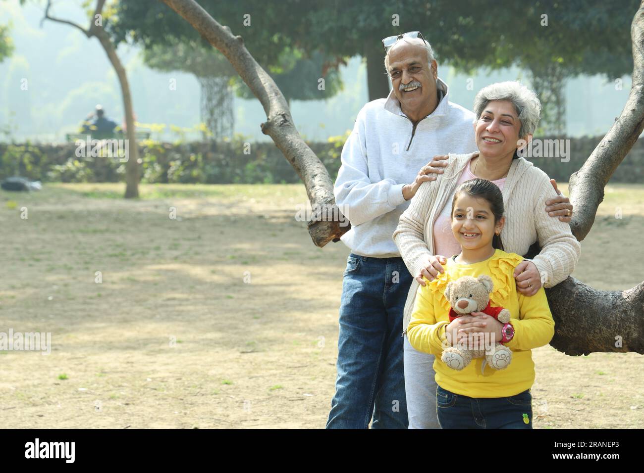 Nonno che si diverte con la nipote nel parco circondato da verde e serenità. Stanno trascorrendo un momento gioioso e allegro insieme Foto Stock