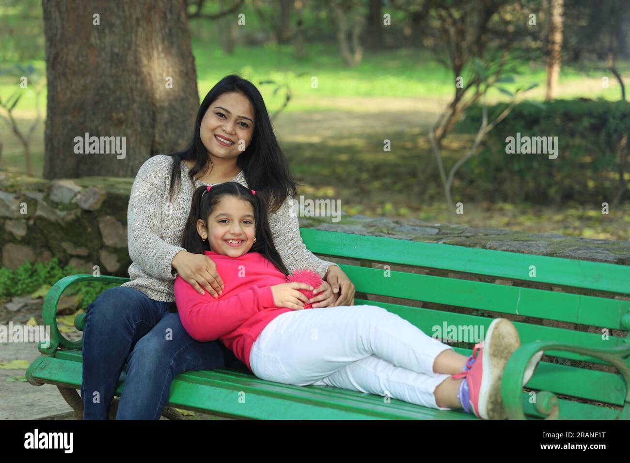 Madre e figlia che si divertono nel parco immerso nel verde e nella serenità. Stanno trascorrendo momenti felici e allegri insieme in un ambiente verde. Foto Stock