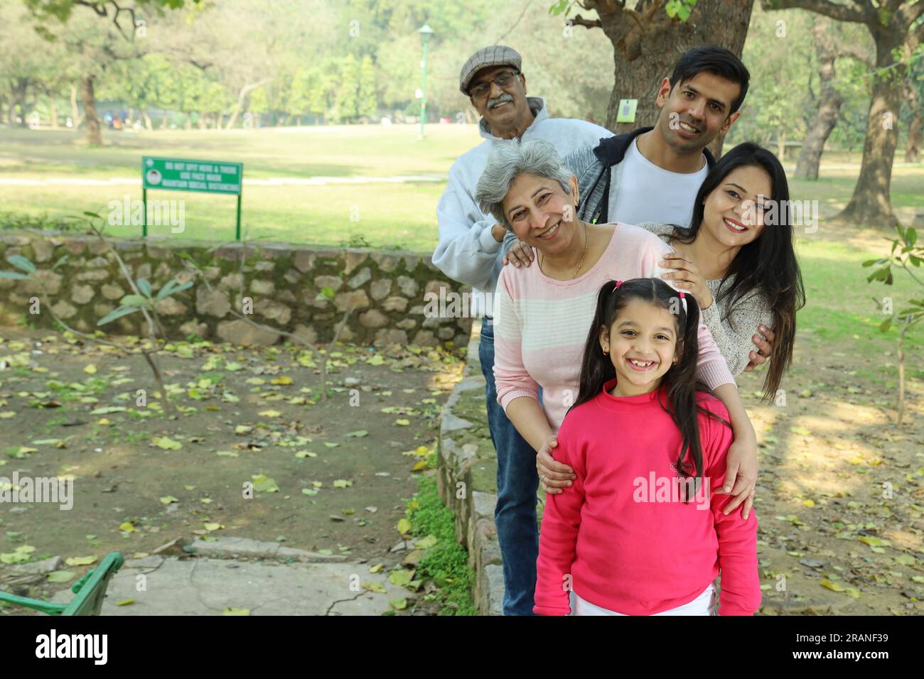 Nonni che si divertono con la nipote nel parco, circondato dal verde e dalla serenità. Stanno trascorrendo momenti gioiosi e allegri insieme nel verde. Foto Stock