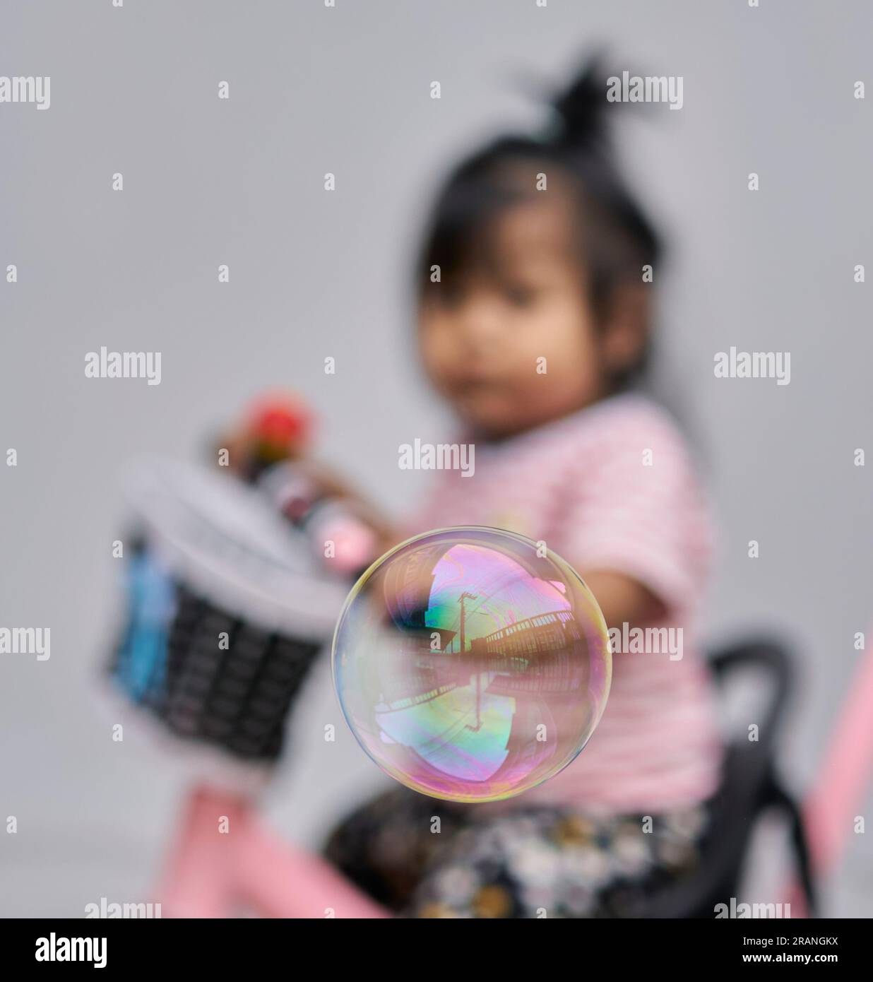 Una bolla che galleggia di fronte a un bimbo sfocato, su una bicicletta, il tempo del concept è breve. Foto Stock