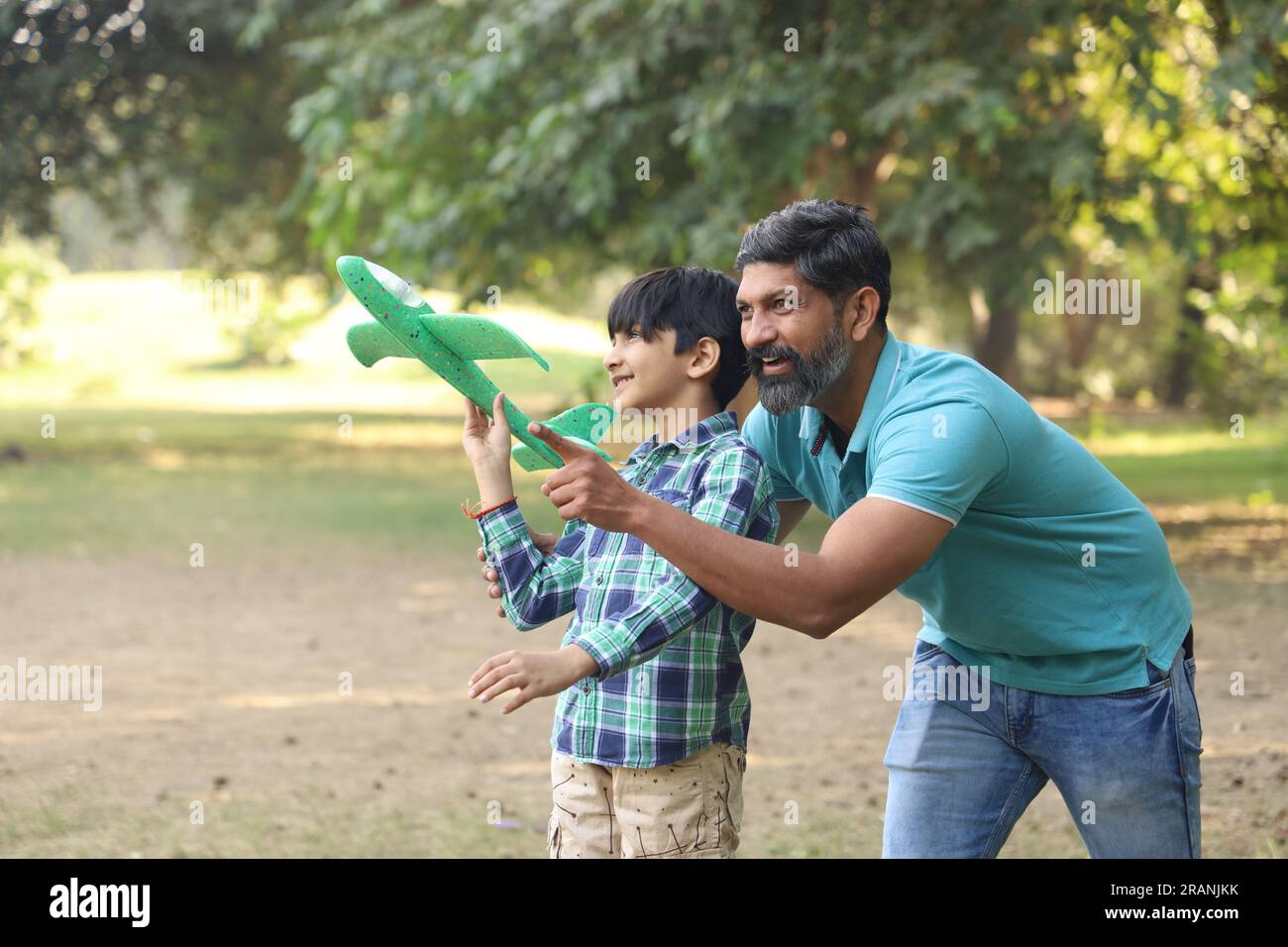 la famiglia si diverte in un parco. Stanno preparando il loro figlio e addestrandolo per un futuro migliore nello sport.cercando di far volare il bambino sull'aereo Foto Stock