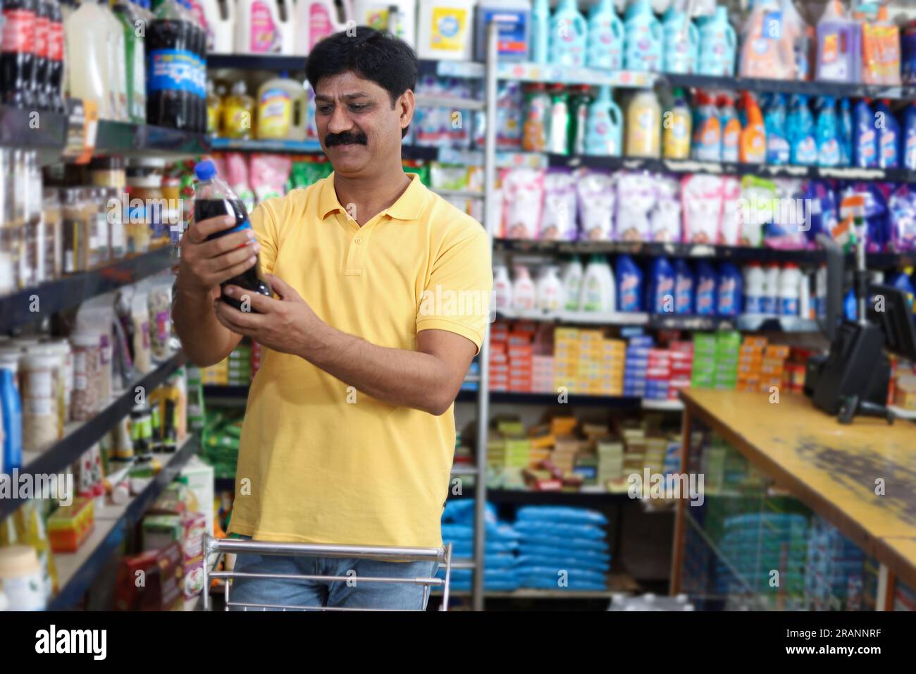 Uomo felice che acquista in un negozio di alimentari. Comprare della spesa per casa in un supermercato. esame di un prodotto Foto Stock