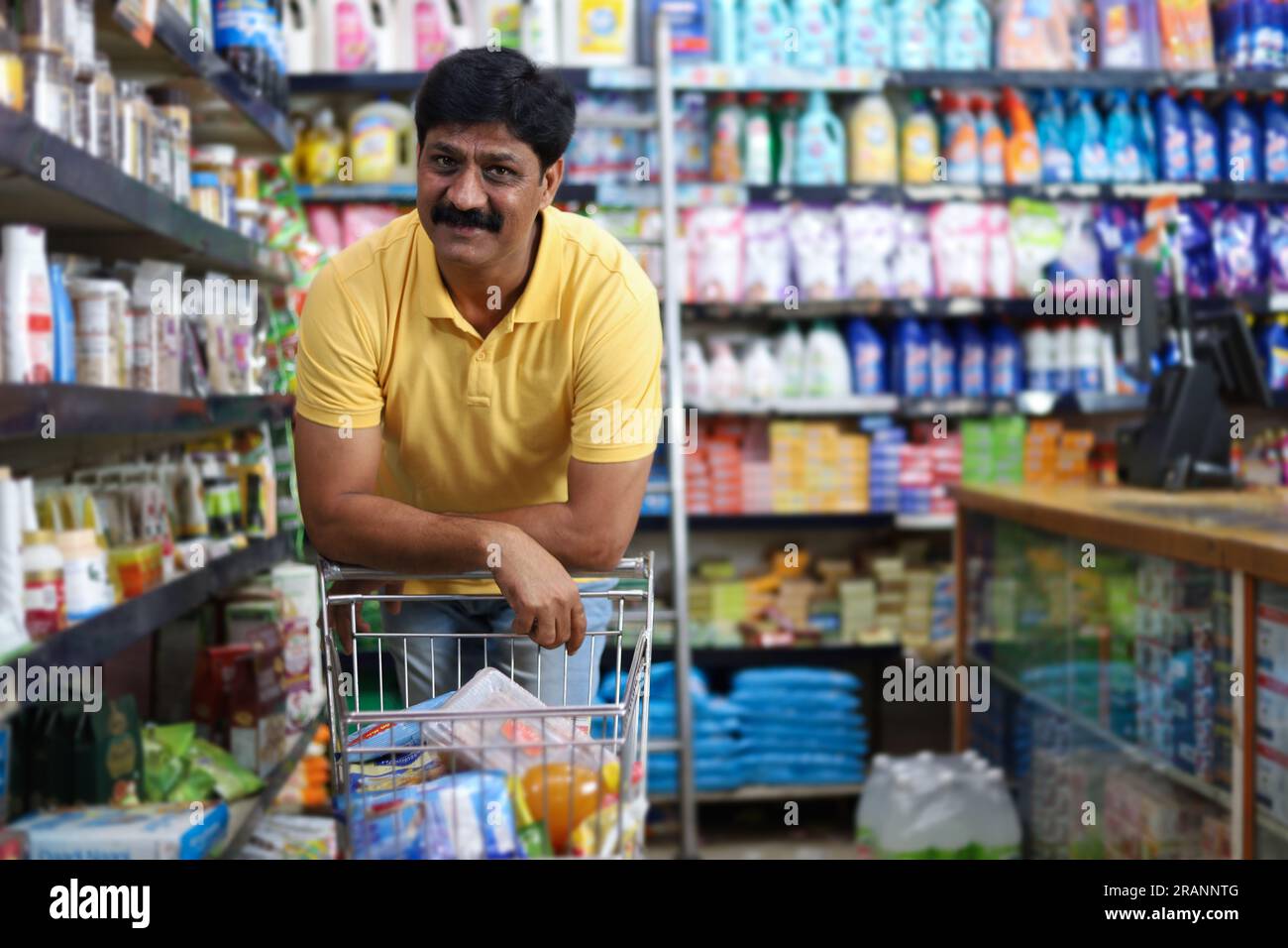 Un indiano che acquista in un negozio di alimentari. Comprare la spesa per la casa in un supermercato.pensare cosa acquistare Foto Stock