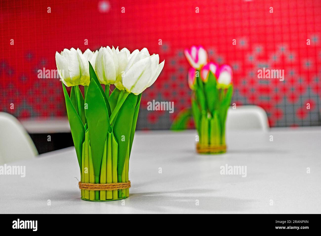 bouquet di tulipani bianchi su un tavolo con interno rosso. Atmosfera natalizia Foto Stock